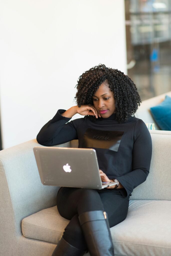 pexels-photo-1181348-1181348 A woman using a laptop while sitting on a sofa in a modern office space.